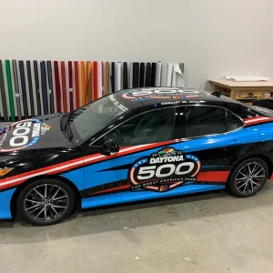 Black and blue race car parked in a garage with a logo on the side