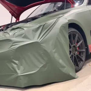 Car with loose green wrap and an open hood