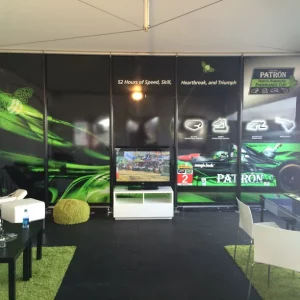 Room with five green and black panels with sponsor logos, TV, and furniture