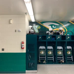 Room with white and green walls and images of football players and helments