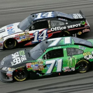 Two race cars driving with logos printed on the sides