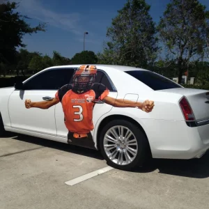 White car in parking lot with a football player on the side